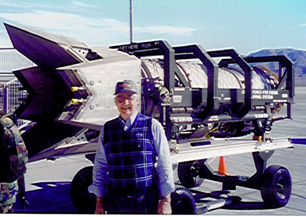 Roadrunner President Roger Andersen posing with engine of F-22